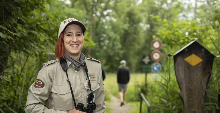 Die Rangerin Florine Leuthardt steht vor einem Wanderweg