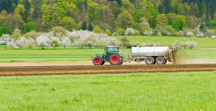 Traktor spritzt Gülle aufs Feld © AdobeStock / Jürgen Fälchle