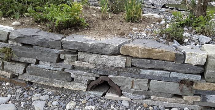 Trockenmauer im Garten mit offenen Fugen und extra eingebauten Nischen