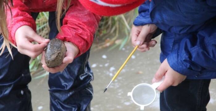 Kinder untersuchen einen Stein aus dem Bach cr_Ursina El Sammra