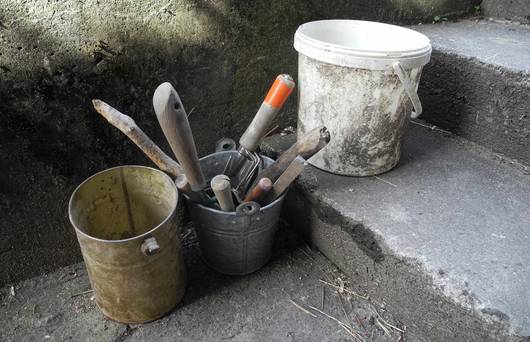 Leere Eimer, ein Kessel mit Gartenwerkzeug