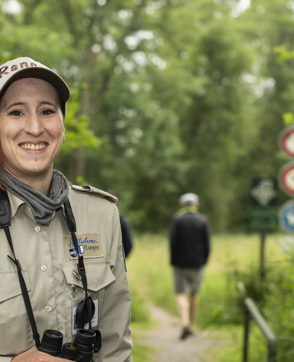 Die Rangerin Florine Leuthardt steht vor einem Wanderweg